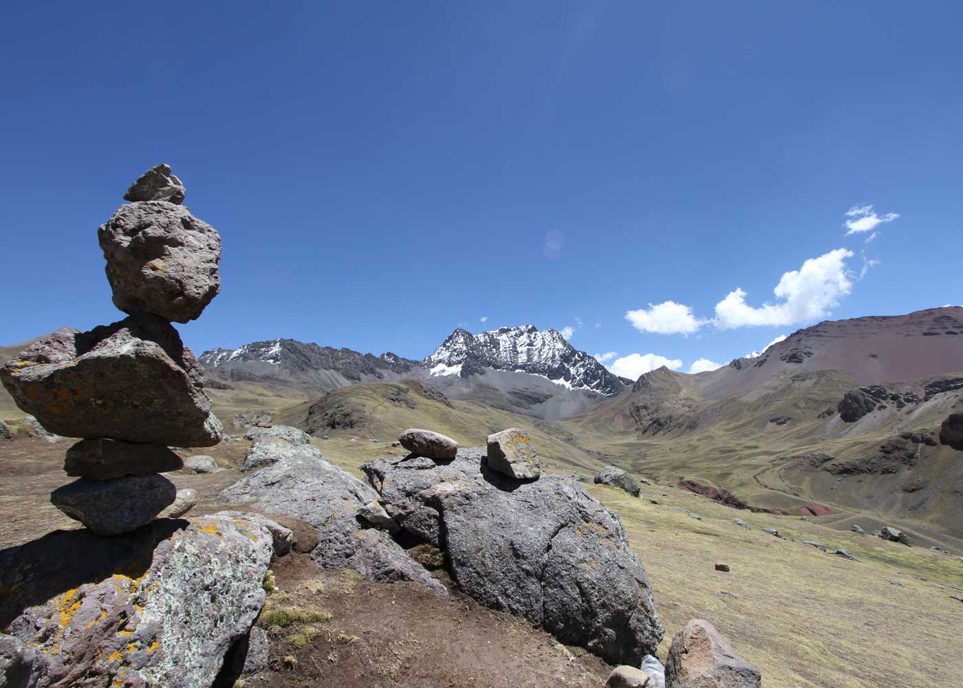 Stone trail marker overlooking snow-capped Andean peaks near Cusco