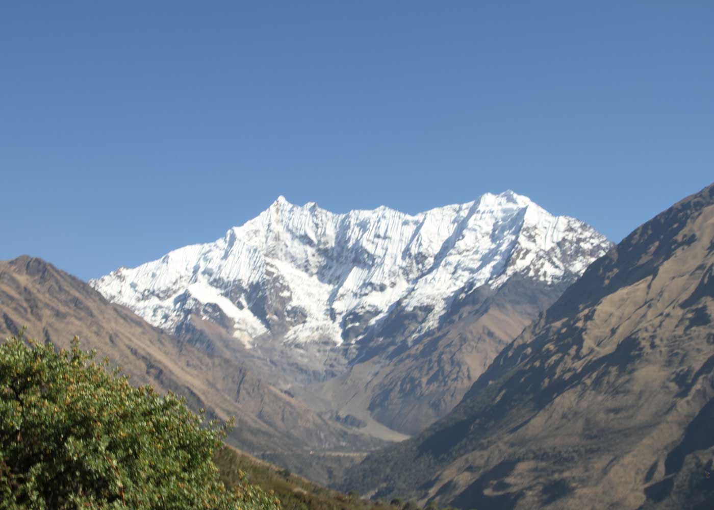 Snow and glacier-covered summit of Salkantay rising above a green Andean valley