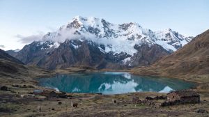 Snow-capped Ausangate mountain reflected in a turquoise glacial lake in Peru