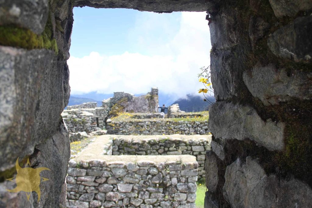 Inca ruins and terraced enclosures framed through a trapezoidal stone doorway