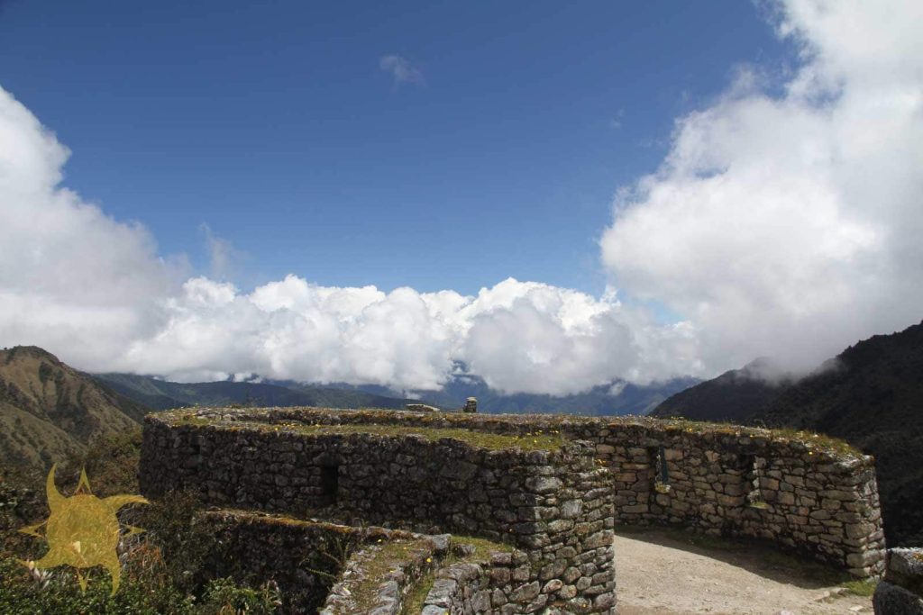 The curved stone walls of Runkurakay beneath a rising cloud bank