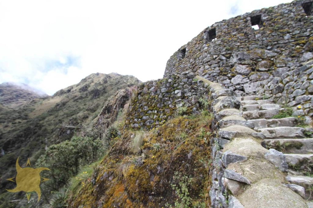 A steep stone stairway climbing to the curved walls of Sayacmarca