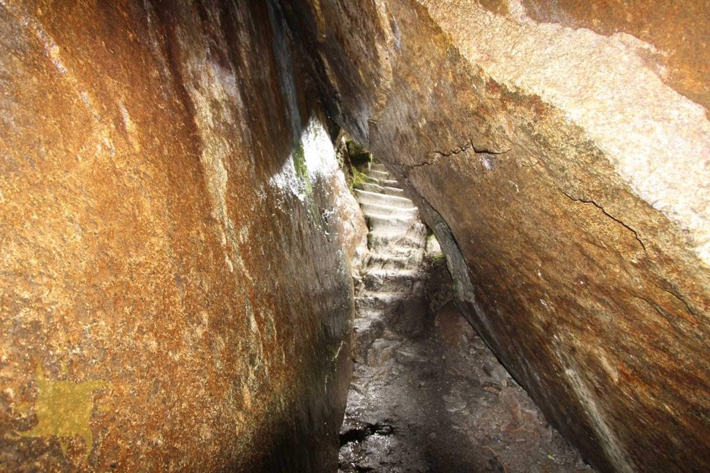 Carved stone steps climbing through the narrow Inca tunnel in the granite