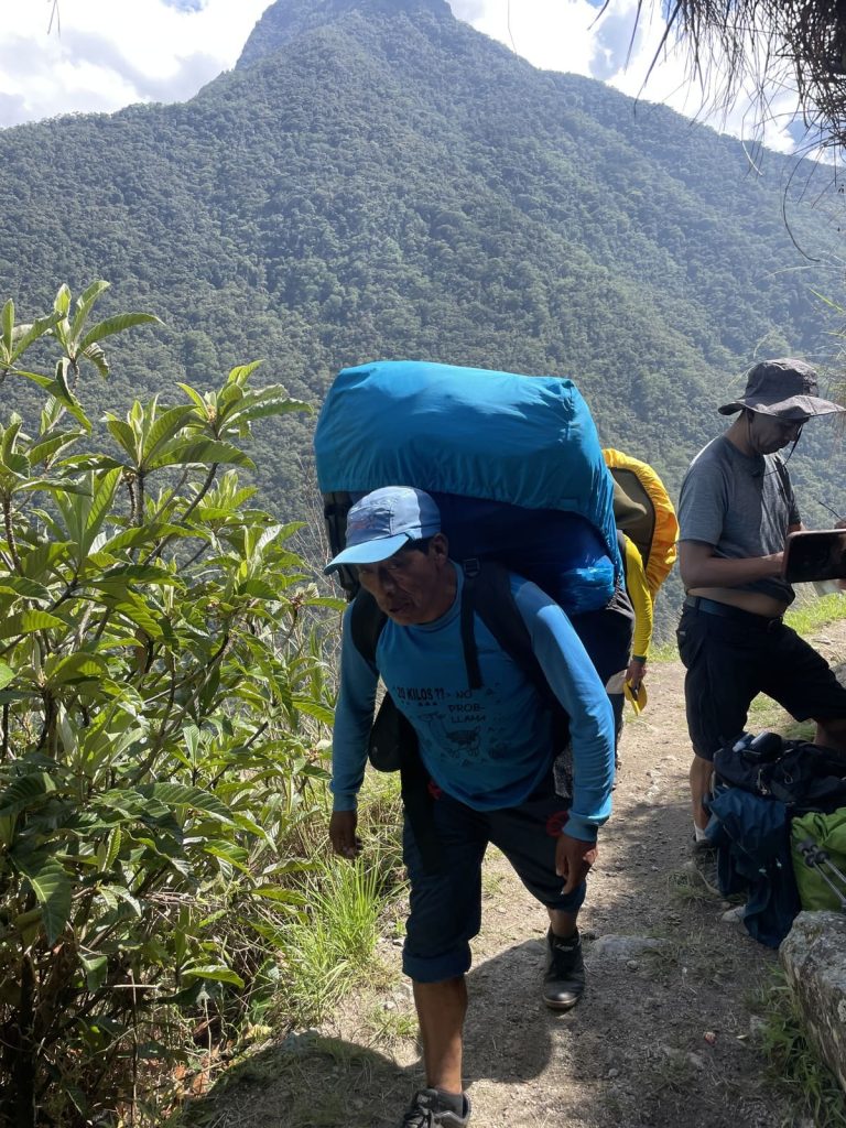 Inca Trail porters carrying their loads up the trail beside trekkers