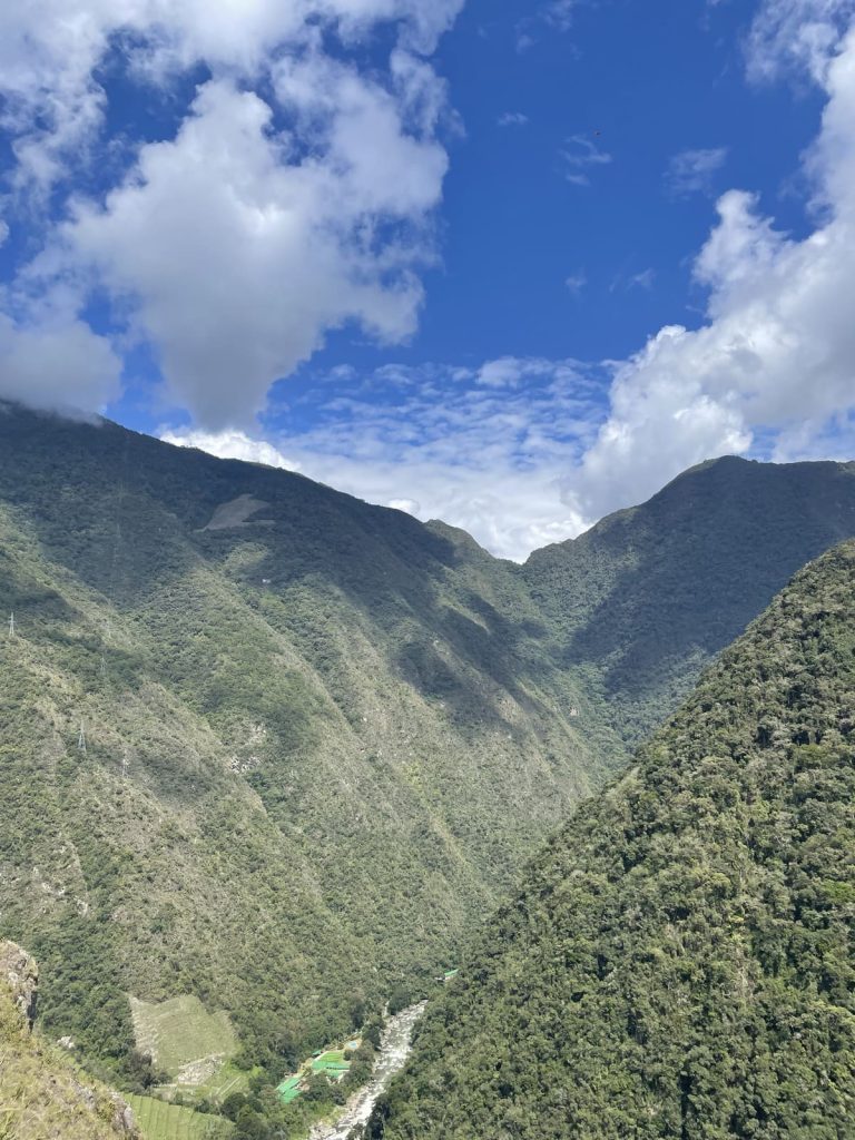 Forested slopes of the Urubamba canyon under a blue sky, seen from the trail toward Wiñay Wayna