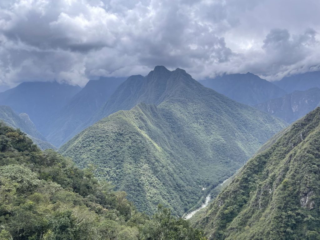 Green peaks rising above the Urubamba River canyon under heavy cloud